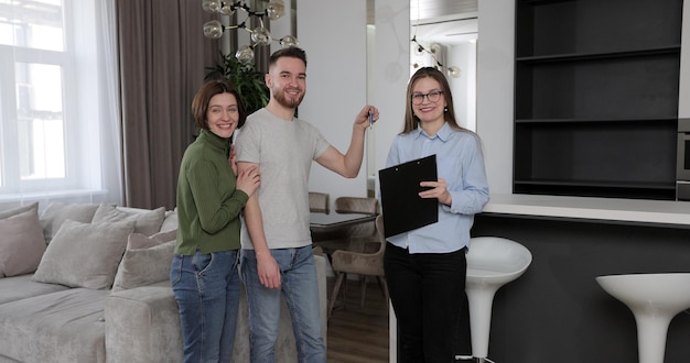 Zdjęcie agent nieruchomości podpisuje umowę i daje klucze do domu szczęśliwej parze para przeprowadza się do nowego mieszkania koncepcja nieruchomości