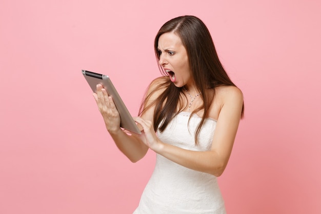 Agresywna zła kobieta w białej sukni krzyczy pracując na cyfrowym tablecie