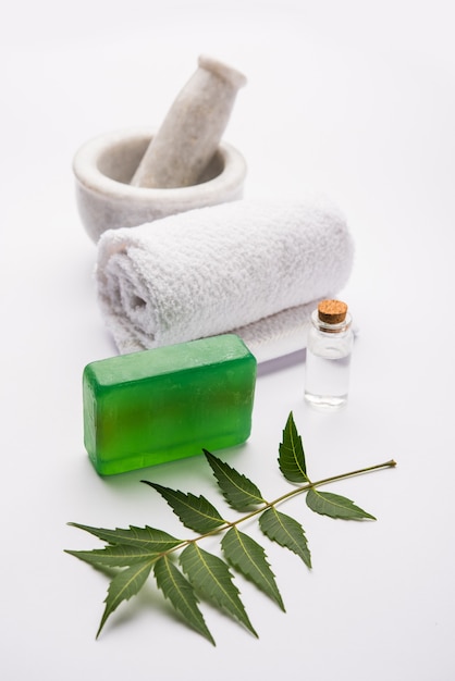 Ajurwedyjskie mydło do kąpieli Neem na bazie Azadirachta indica, ułożone z liści, zaprawy, ręcznika i olejku eterycznego. Selektywne skupienie