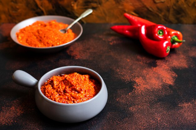 Ajvar - bałkańska przekąska z pieczonej papryki. Kuchnia serbska i bałkańska. Ajvar w misce, papryka w proszku i świeża papryka w tle. Bogaty kolor złota i miedzi. Miejsce na tekst