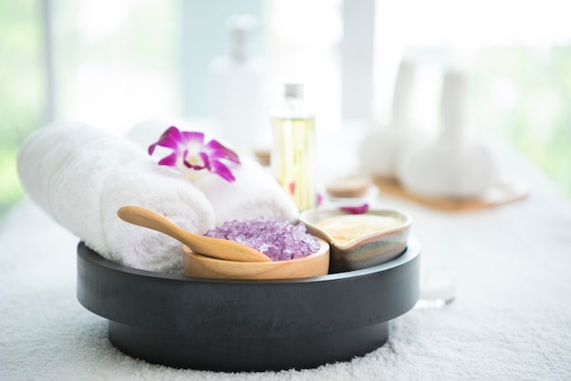 Akcesoria do spa aromatyczna świeca, kwiat orchidei, peeling solny i ręcznik.