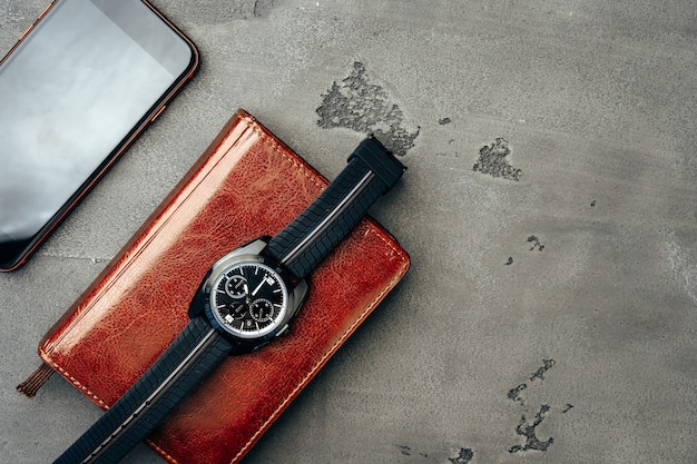 Zdjęcie akcesoria męskie, takie jak smartfon i zegarek na ciemnoszarym stole z bliska