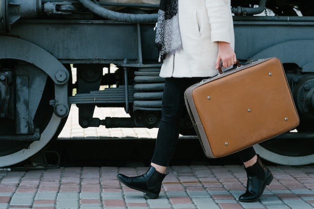 Akcesoria mody podróżnej. hipster stylu vintage retro walizka. cel podróży transportowej. kobieta na stacji kolejowej.