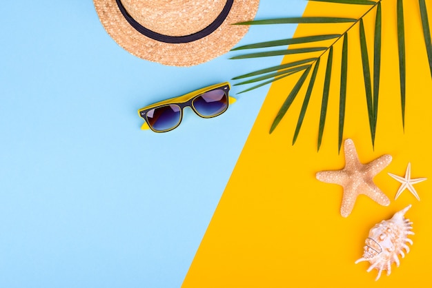 Akcesoria plażowe: okulary i czapka z muszlami i morskimi gwiazdami na kolorowym tle. Lato w tle