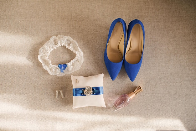 Akcesoria ślubne panny młodej to białe i niebieskie buty pierścień poduszki perfumy podwiązka i kolczyki