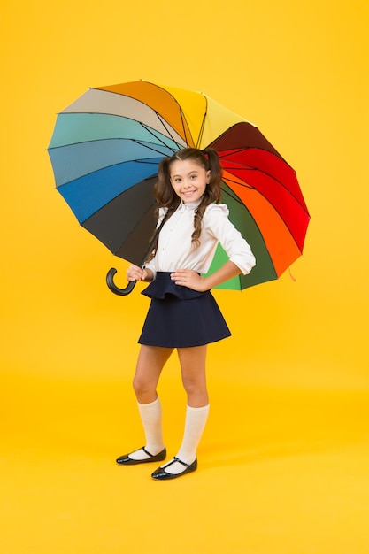 Akcesoria zwiększające bezpieczeństwo spaceru do szkoły w deszczu Małe dziecko trzymające kolorowy parasol Akcesoria przeciwdeszczowe Dziewczynka z modnym dodatkiem na deszczową pogodę Najfajniejszy dodatek na ulicy