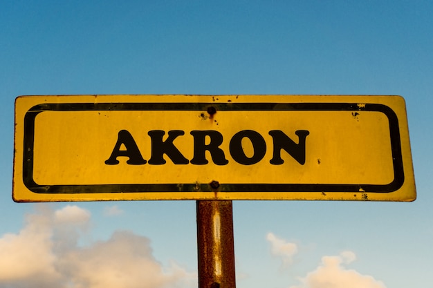 Akron miasta żółty stary znak z niebieskim niebem