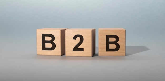Zdjęcie akronim b2b- business to business. drewniane kostki z literami na białym tle na szarym tle. obraz koncepcji biznesowej.