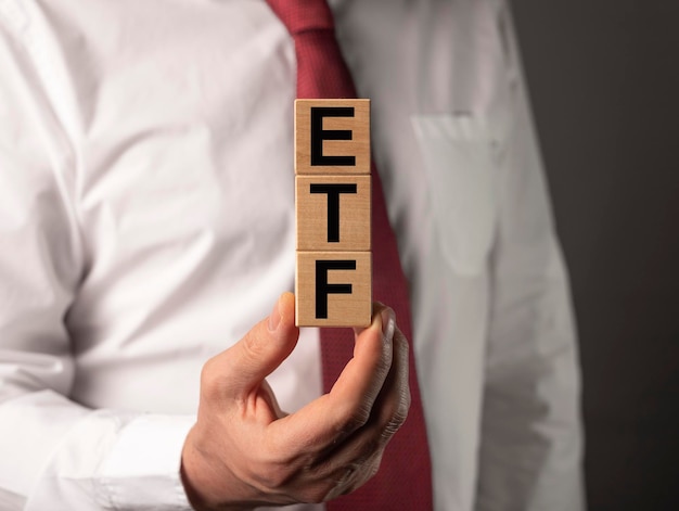 Akronim inwestora ETF na drewnianych kostkach w dłoni inwestora