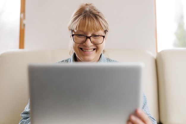 Aktywna dojrzała kobieta korzystająca z laptopa do pracy zdalnej z domowego biura Wideokonferencja Spotkanie wideo Starszy nauczyciel prowadzi seminarium internetowe