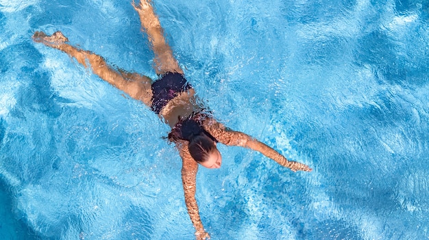 Aktywna młoda dziewczyna w basenie widok z lotu ptaka z góry młoda kobieta pływa w niebieskiej wodzie
