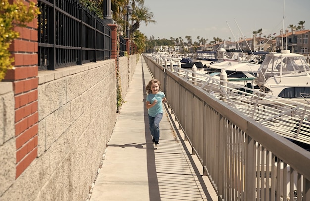 Aktywny chłopiec dzieciak cieszy się letnimi wakacjami biegając na promenadzie!