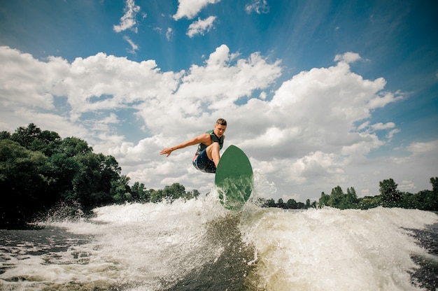 Aktywny Człowiek Wakesurfing Na Desce W Dół Rzeki Na Tle Pochmurnego Nieba I Drzew