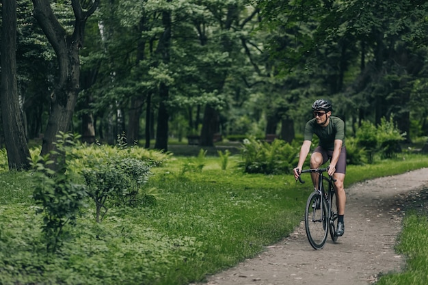 Aktywny facet w kasku i okularach cieszący się poranną jazdą na rowerze