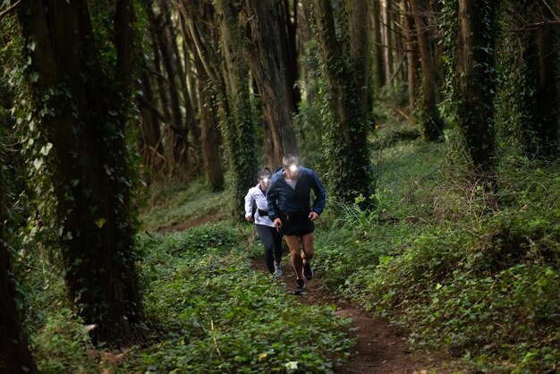 Aktywny Mężczyzna I Kobieta Jogging W Lesie. Dwóch Sportowych Ludzi W Sportowych Ubraniach, ćwiczenia Na świeżym Powietrzu O Zmierzchu. Sport, Koncepcja Hobby