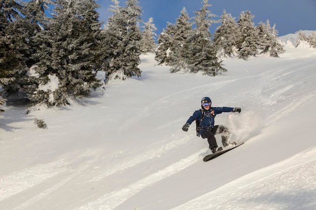 Aktywny mężczyzna jeździ na snowboardzie freeride na zaśnieżonym zboczu w alpejskim terenie backcountry w Karpatach