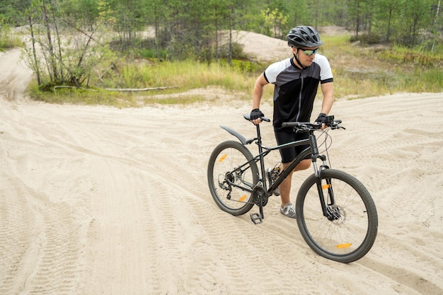 Aktywny sport mężczyzna na rowerze górskim w kasku i sprzęt na drodze w zielonym lesie