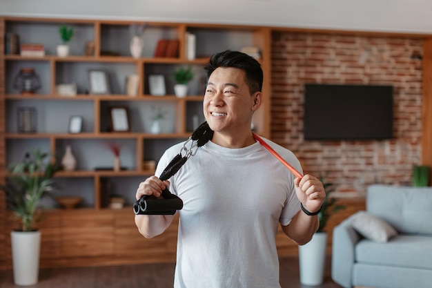 Aktywny sportowy styl życia Szczęśliwy azjatycki dojrzały mężczyzna trzymający opaski oporowe wiszą na szyi