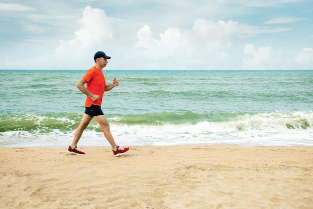 Aktywny starszy mężczyzna zbiega w dół piaszczystej plaży Zdrowy styl życia Jogging