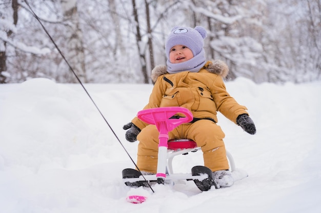 Aktywny tryb życia zimą Maluch zimą ciepłe ubrania jeździ na dziecięcym ratuszu, który jest ciągnięty na linie