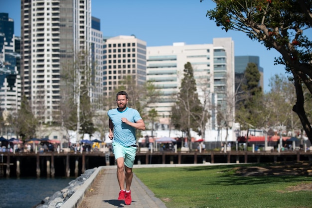 Aktywny zdrowy biegacz biegający na świeżym powietrzu Sport i zdrowy styl życia Młody wysportowany mężczyzna biegający w miejskim parku miejskim