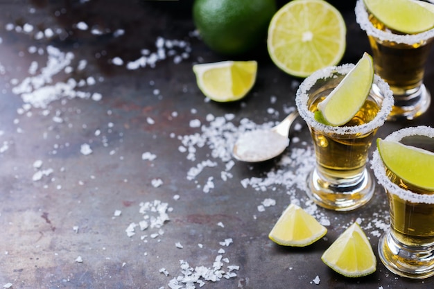 Alkohol fast foodów party wakacje koncepcja Złota meksykańska tequila strzał na grunge czarny stół z solą i limonką Kopiuj tło