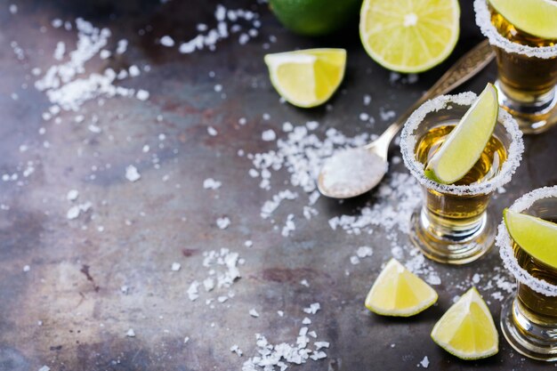 Alkohol fast foodów party wakacje koncepcja Złota meksykańska tequila strzał na grunge czarny stół z solą i limonką Kopiuj tło
