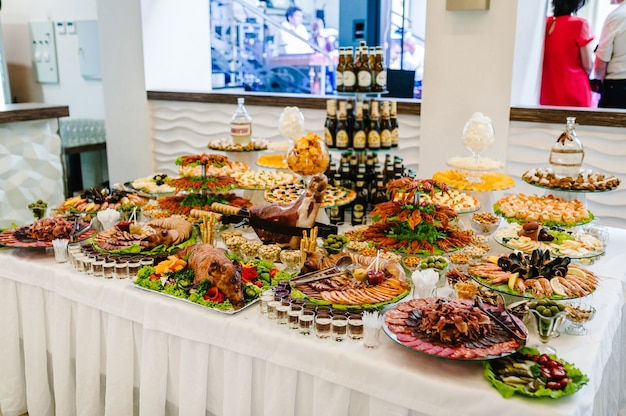 Alkohol i jedzenie. Piwo z przekąskami na stole. Różne potrawy gotowane na grillu na drewnianym stole w słoneczny dzień, raki, kalmary, owoce morza, frytki, orzechy. Koncepcja żywności w pomieszczeniu.