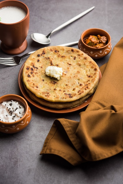 Aloo Paratha lub Indian Potato Faszerowane Flatbread z masłem na wierzchu. Podawany ze świeżym słodkim lassi, chutneyem i piklami. selektywne skupienie