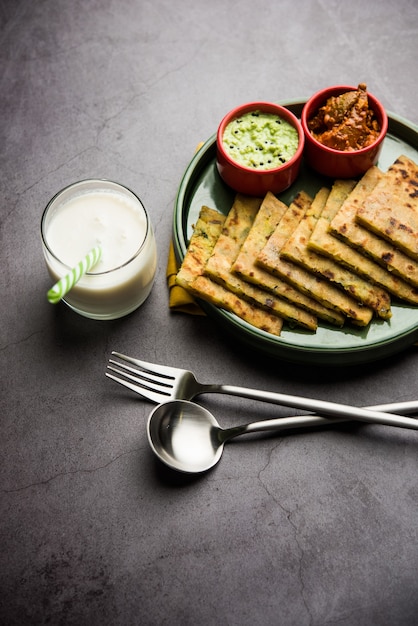 Aloo Paratha lub Indian Potato Faszerowane Flatbread z masłem na wierzchu. Podawany ze świeżym słodkim lassi, chutneyem i piklami. selektywne skupienie