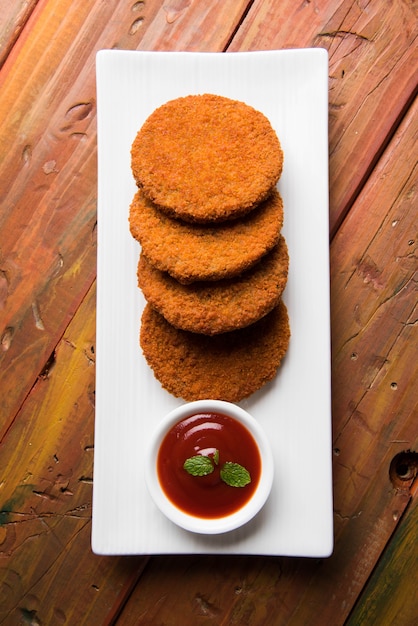 Aloo Tikki lub Patties lub Cutlet to popularna przekąska lub przekąska z Indii, Podawana z Ketchupem Pomidorowym lub Chutney Imli na nastrojowym tle. Selektywne skupienie