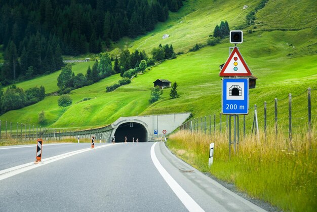 Alpejska droga prowadząca do tunelu górskiego Znaki drogowe