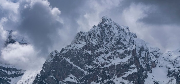 Alpejski szczyt śnieżny na tle ponurego nieba Dolomity Włochy wiosna w górach Pojęcie i idea zmienności pogody w górach