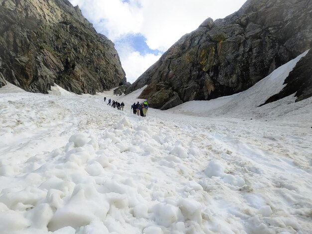 Alpiniści idący po pokrytym śniegiem zboczu góry