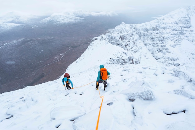 Alpiniści wspinający się na ośnieżony grzbiet Liathach w Szkocji