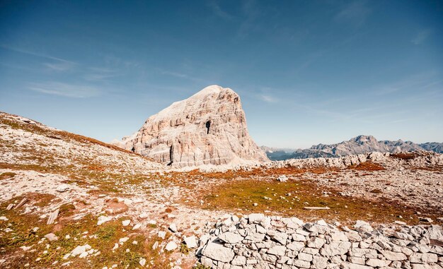 Alpinista na stromej i odsłoniętej Via Ferrata Col dei Bos w pobliżu passo falzarego Majestatyczny krajobraz alpejskiej czerwonej jesieni Passo Falzarego Tofana we Włoszech w pobliżu Cortina d'Ampezzo