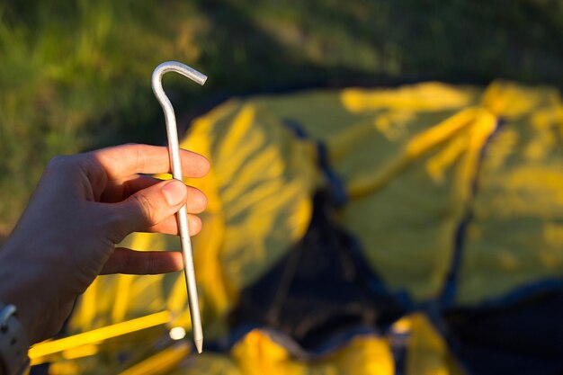 Zdjęcie aluminiowe kołki do instalacji żółtego namiotu turystycznego w ręcznym bliskim, lekkim rozmiarze