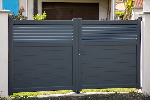 Aluminiowy portal drzwiowy z podwójną stalową bramą szarego domu na przedmieściach domu w mieście
