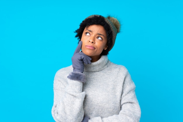 Amerykanin afrykańskiego pochodzenia kobieta z zima kapeluszem nad odosobnioną błękit ścianą