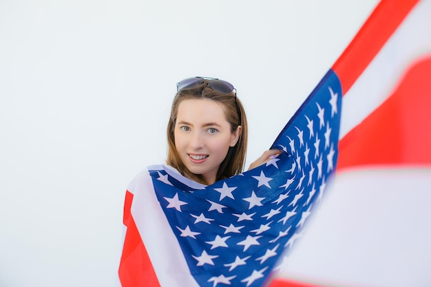 Amerykańska dziewczyna Szczęśliwa młoda kobieta w okularach przeciwsłonecznych w kształcie serca na flagi USA na białym tle
