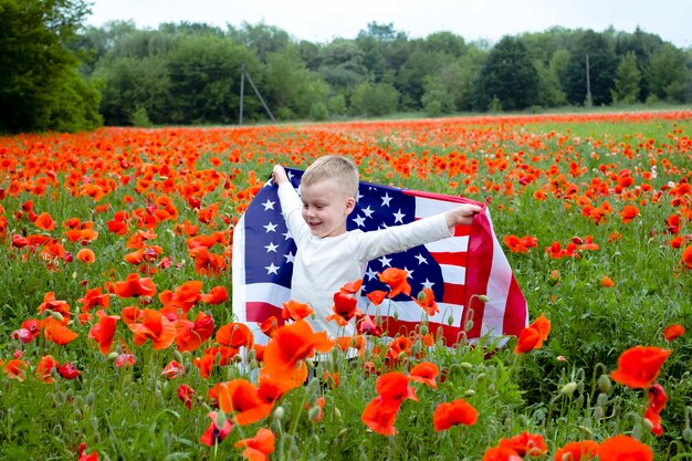 Amerykańska flaga w rękach dziecka wśród pola czerwonych maków