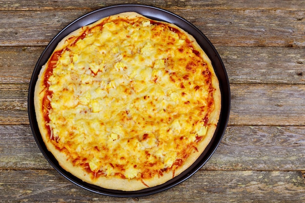 Amerykańska pizza z pepperoni, mozzarellą i sosem pomidorowym. Pizza na drewnianym stole,