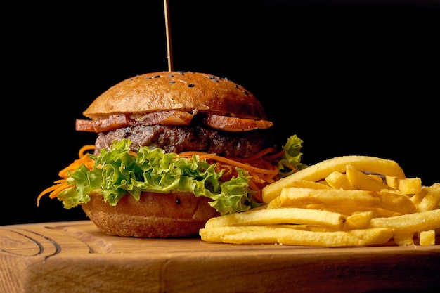 Amerykański fast food burger z frytkami i sosem. Ciemne drewniane tło. Selektywne skupienie.