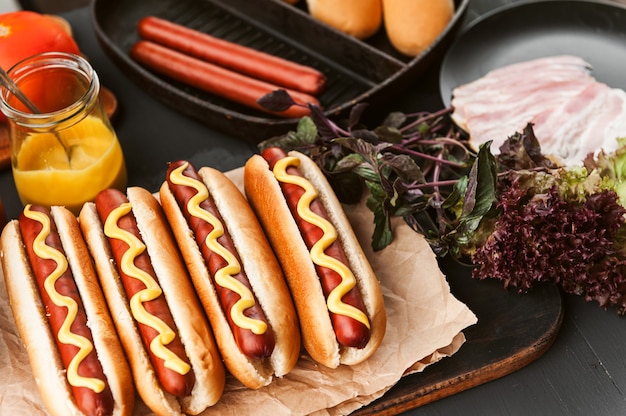 Amerykański hot dog z składnikami na ciemnej drewnianej powierzchni