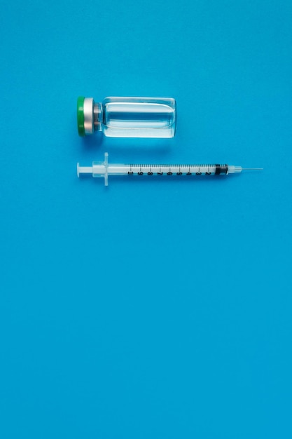 Zdjęcie ampułka strzykawki z lekiem na niebieskim tle