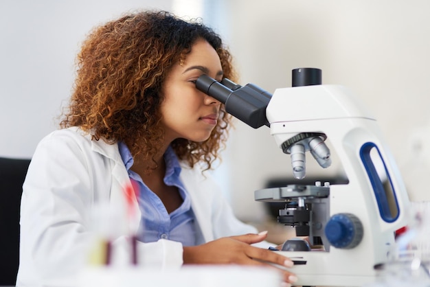 Analiza danych mikroskopowych Przycięte zdjęcie młodej kobiety-naukowca patrzącej w mikroskop