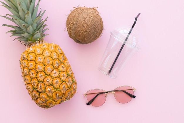 Ananas, kokos i okulary przeciwsłoneczne na jasnym różowym tle Witam koncepcja lato