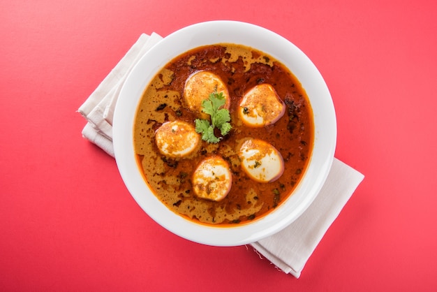 Anda Curry lub Egg Masala sos, indyjskie pikantne jedzenie lub przepis, podawane z ryżem Jeera, roti lub naan, selektywne skupienie. Nad kolorowym lub drewnianym blatem