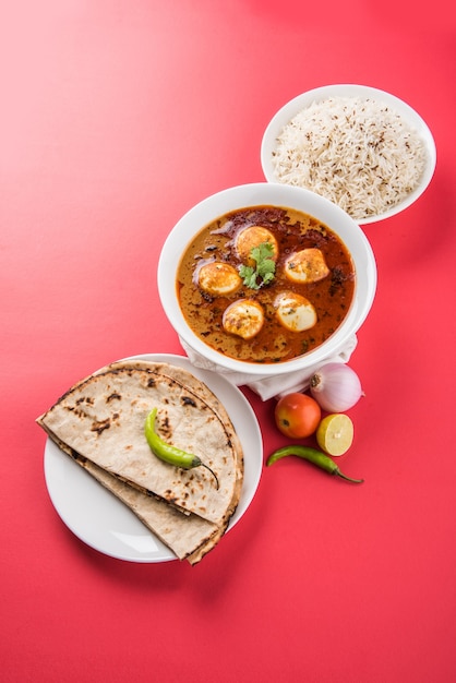 Anda Curry lub Egg Masala sos, indyjskie pikantne jedzenie lub przepis, podawane z ryżem Jeera, roti lub naan, selektywne skupienie. Nad kolorowym lub drewnianym blatem