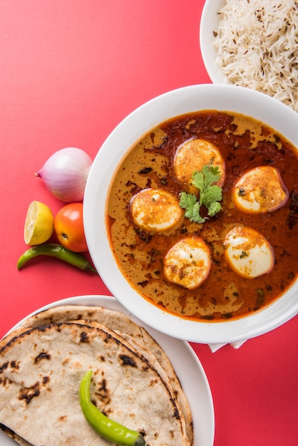 Anda Curry lub Egg Masala sos, indyjskie pikantne jedzenie lub przepis, podawane z ryżem Jeera, roti lub naan, selektywne skupienie. Nad kolorowym lub drewnianym blatem